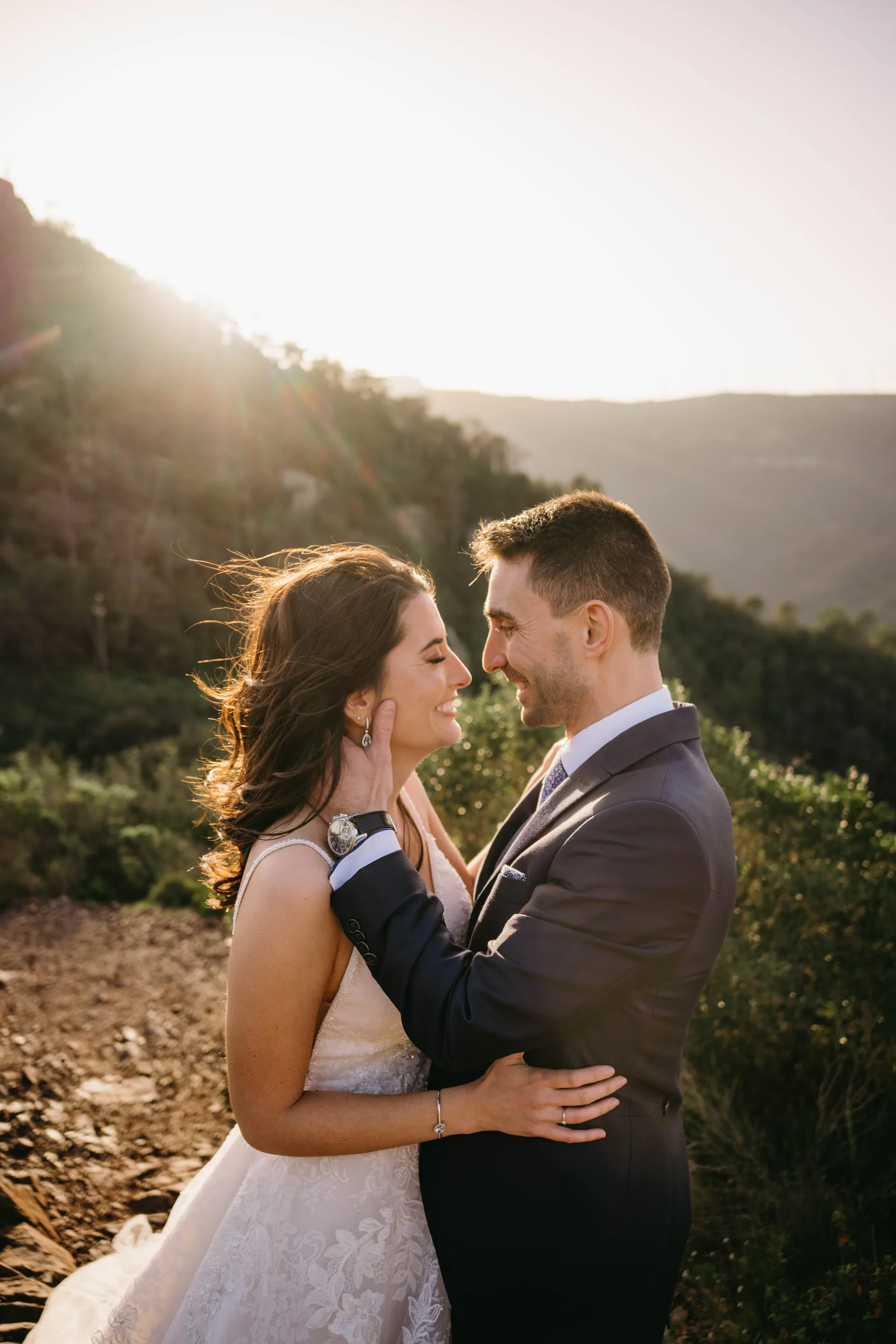 Novios abrazados a contraluz en la montaña al atardecer